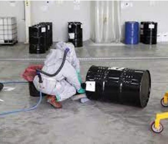worker in a biohazard suit cleaning a chemical spill